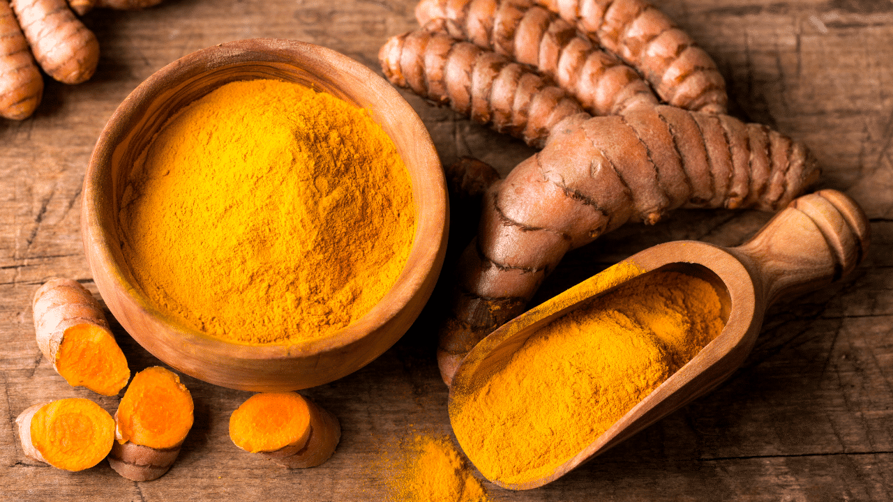 curcuma : racines et poudre de curcuma sur fond en bois